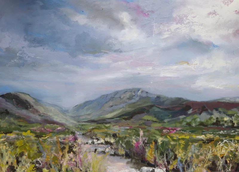 A path winding through green and purple moorland into a valley between mountains, under a soft grey sky