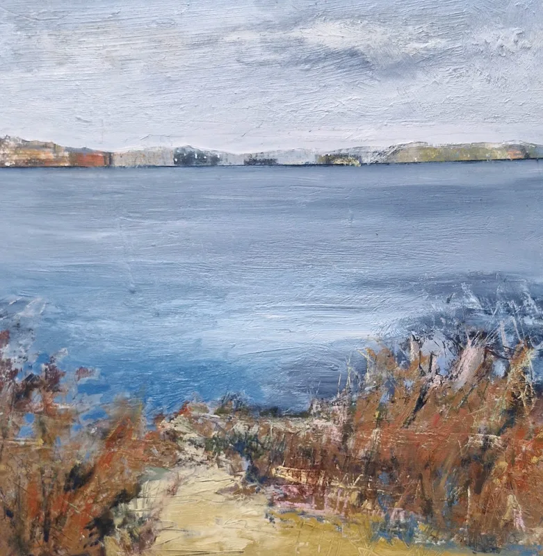 A sandy path between russet grasses leading down to wide pale blue water and a far shore of low cliffs